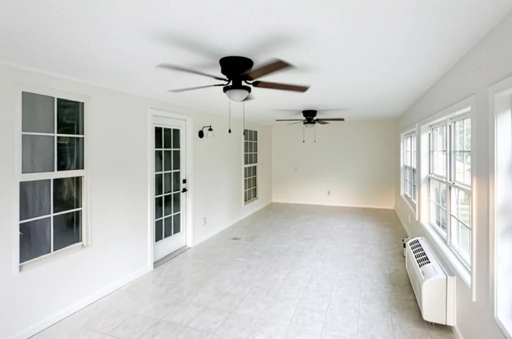 Bright sunroom addition with ceiling fan and large windows